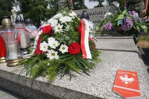 Grób powstańca udekorowany kwiatami i plakietką