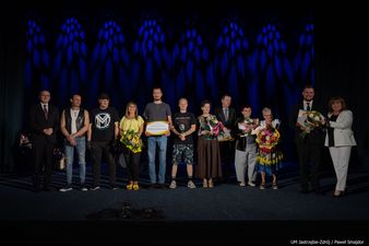 nagrodzeni stoją na scenie wraz z otrzymanymi kwiatami