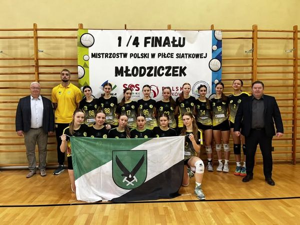 Pozująca do zdjęcia drużyna młodziczek z trenerami i działaczami, trzymająca flage miasta Jastrzebie-Zdrój