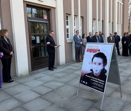 Prezydent Miasta Michał Urgoł wraz z innymi przedstawicielami miasta zgromadzona przed budynkiem Muzeum Miejskiego, na pierwszym planie bilboard prezentujący wystawę na temat Danuty Siedzikówny