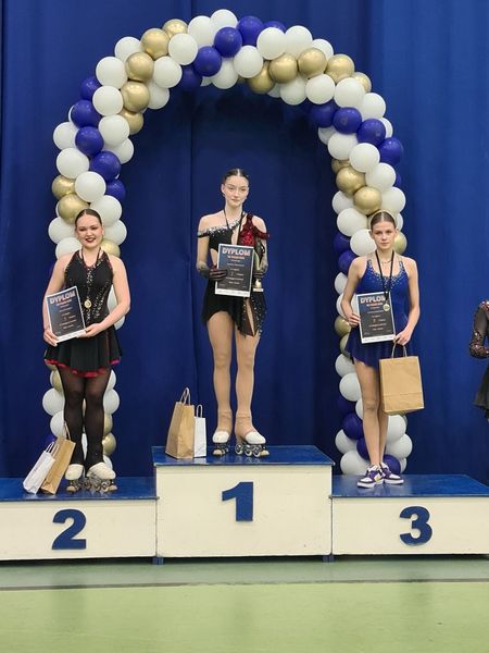 Zuzanna Jaskulska na 3 stopniu podium, obok rywalek z medalem, dyplomem i torbą z gadżetami