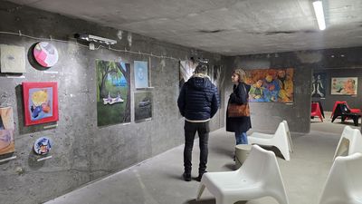 Kobieta i mężczycna oglądający jeden z obrazow na wystawie.