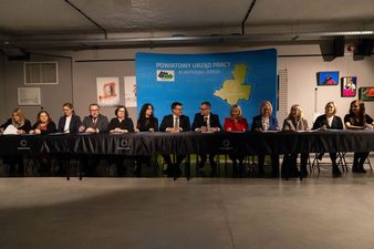 Wszyscy uczestnicy spotkania siedzący za długim stołem, za nimi ścianka z napisem Powiatowy Urząd Pracy w Jastrzębiu-Zdroju