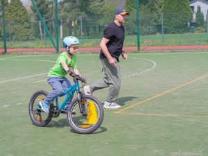 Chłopczyk z astystą meżczyzny jadący na rowerze