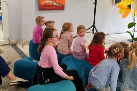 Dzieci siedzą tyłem, jedna dziewczynka się odwróciła