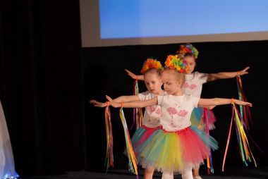 dzieci i nauczycielka przebrane za kwiaty na scenie