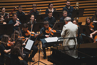 Muzycy Beskid Youth Orchestra na scenie dyryguje Paweł Kotla