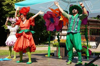 Kobiety i mężczyzna w kolorowych tańczą na placu pod parasolem miejskim