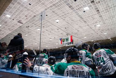 Widok na ławkę rezerwowych zawodników JKH zaa szyby