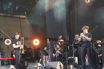 dwóch mężczyzn jeden z puzonem drugi z trąbką graja na scenie