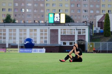 Zawodnik GKS-u siedzi na murawie i zakrywa twarz. W tle tablica świetlna pokazuje wynik 0:2.