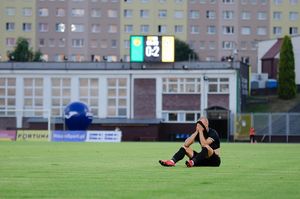 Zawodnik GKS-u siedzi na murawie i zakrywa twarz. W tle tablica świetlna pokazuje wynik 0:2.