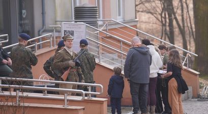 Zgromadzeni uczestnicy gry terenowej, część z nich strojach wojskowych, jeden trzyma broń