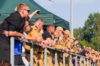 Grupa ludzi w tym umundurowani strażacy oglądają mistrzostwa z trybun