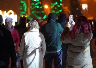 Widok z tyłu na uczestników imprezy. Na pierwszy planie kobieta nagrywająca otoczenie smartfonem