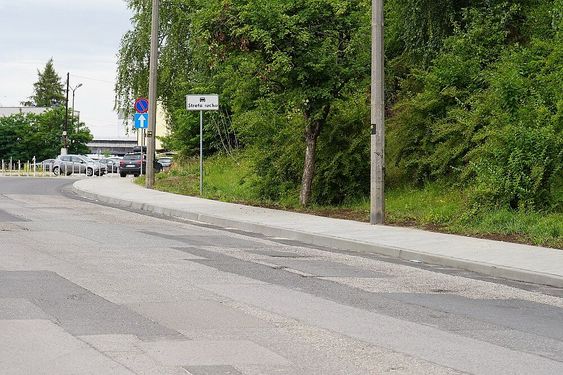 Szersza perspektywa nowej nawierzchni chodnika przy ul. Górniczej oraz ustawione znaki drogowe wskazujące na strefę ruchu