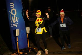 Kobieta ubrana w uśmiechnięte buźki cieszy sie po wbiegnięciu na linie mety