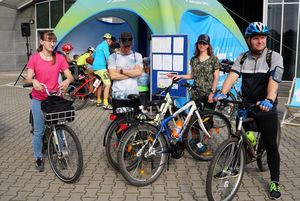 Grupa rowerzystów przed halą widowiskowo-sportową