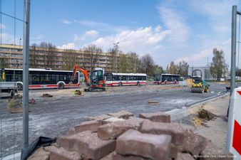 kostka brukowa na pierwszym planie w tle widoczne koparka walec i autobusy