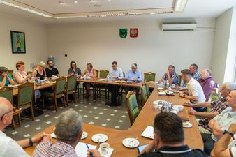 przewodniczący osiedli oraz sołtysi siedzą w sali konferencyjnej podczas spotkania