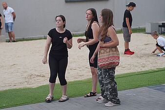 Trzy młode kobiety tańczące na krawędzi strefy z piaskiem podczas imprezy na świeżym powietrzu