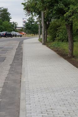 fragment nowo wybudowanego chodnika z kostki brukowej przy ul. Górniczej, biegnącego wzdłuż jezdni oraz rosnących obok drzew