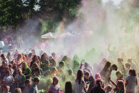 Tłum uczestników zabawy plenerowej spowity gęstą, wielobarwną chmurą proszków holi.