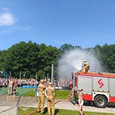 Wóz strażacki polewa ludzi w upalny dzień na Ośrodku Wypoczynku Niedzielnego
