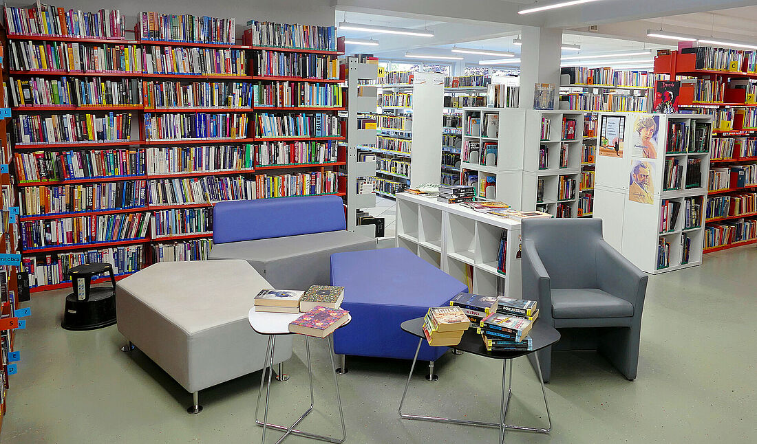 Wnętrze biblioteki miejskiej, stolik, krzesła i półki z książkami