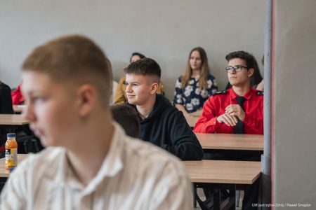 Młodzież siedząca przy stolikach w sali czekająca na rozpoczęcie konkursu