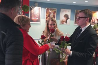 Prezydent wręcza róże pani w holu kina centrum z okazji dnia kobiet