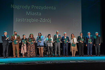 Prezydent Michał Urgoł i drug zastęca prezydenta miasta Andrzej Matusiak wraz z nagrodzonymi nauczycielami stoją na scenie w kinie Centrum podczas uroczystości Dnia Edukacji Narodowej 