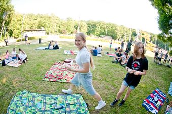 Dziewczyna niesie grillowaną kiełbaskę z chlebem podczas pikniku na trawie