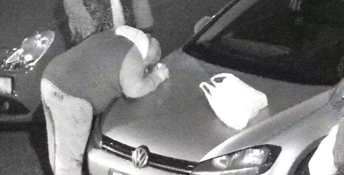 Mężczyzna wciąga proszek z maski samochodu, obok leży reklamówka