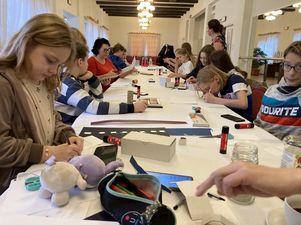 Uczestnicy warsztatów siedzący przy stole i wykonujący prace.