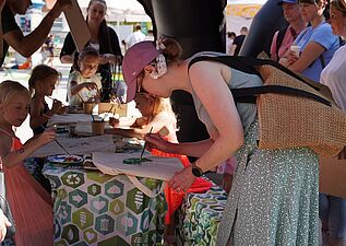 Grupka dzieci i dorosłych malująca torby