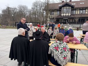 Prezydent michał urgoł stoi przy stoliku i rozmawia z ludźmi podczas śniadania wielkanocnego