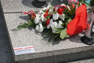 Grób powstańca udekorowany kwiatami i plakietką