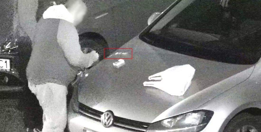 Mężczyzna stoi przy samochodzie, na masce którego leży biały proszek i reklamówka