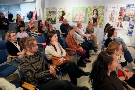 Uczestnicy spotkania siedzą na krzesłach i patrzą przed siebie