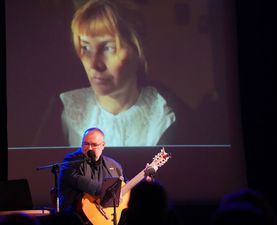 Artysta podczas wystepu, za nim na ekranie wizerunek żołnierki wyklętej