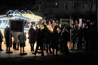 Zbliżenie na czworo muzyków (kobietę grającą na skrzypcach oraz trzech mężczyzn) występujących nocą w świetle iluminacji