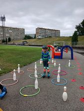 Rolkarz pokonujący tor przeszkód złozony z kregli i małych kółek