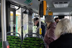 Widok na wnętrze autobusu z pasażerami.