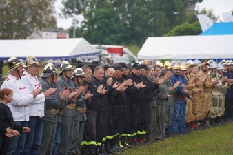 Wszystkie dorosłe drużyny rywalizacji stojące w rzędzie i oklaskujące organizatorów