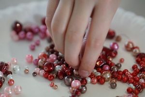 Dłoń sięgająca do pojemnika z koralikami