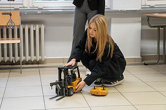 Dziewczyna steruje wózkiem widłowym 