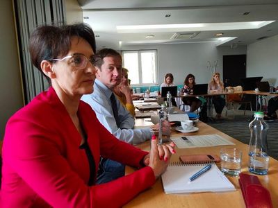 Uczestnicy warsztatów siedzą przy stołach.