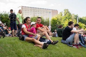 Kibice siedzą na trawie.