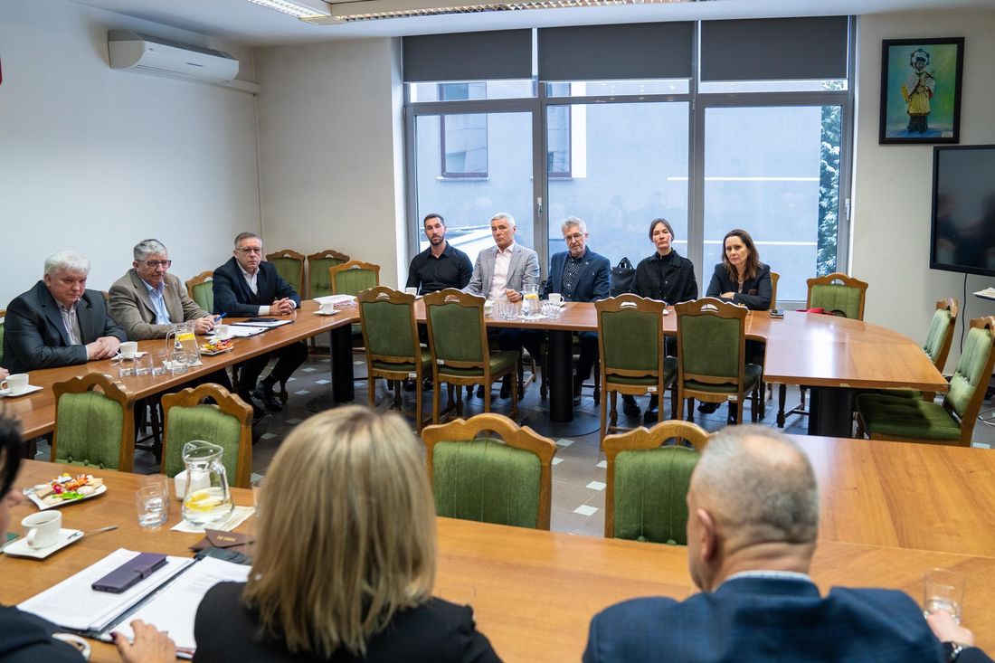 Uczestnicy spotkania siedzą przy stole - widok z dalszej perspektywy